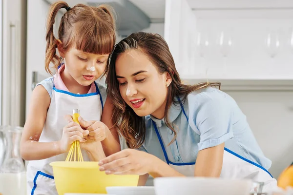 긍정적 여자가 딸에게 달걀에 설탕을 설탕을 바르는 가르치고 있습니다 — 스톡 사진
