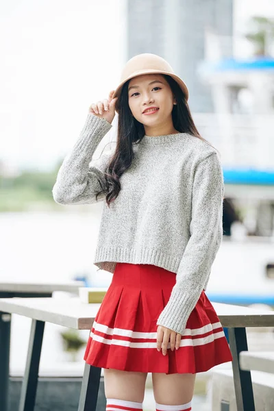 Mini Etek Süveter Şapka Giymiş Gülümseyen Asyalı Kız Öğrencinin Portresi — Stok fotoğraf