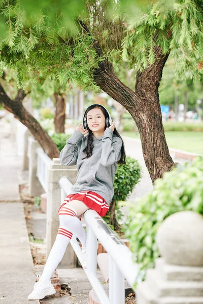 Glückliches Asiatisches Teenager Mädchen Sitzt Auf Geländer Park Und Hört — Stockfoto