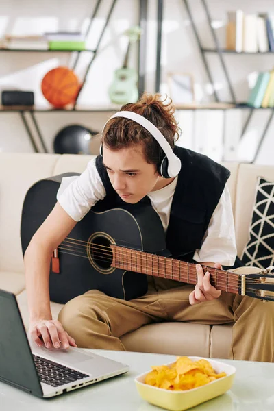 Nastolatek Słuchawkach Bezprzewodowych Jedzący Chipsy Ziemniaczane Podczas Nauki Gry Gitarze — Zdjęcie stockowe