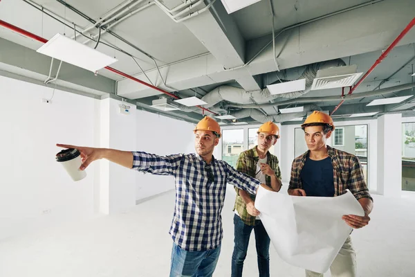 Contractor Cup Coffee His Hand Pointing Pipes Wall Showing Colleagues — Stock Photo, Image