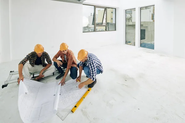 Equipe Jovens Construtores Chapéus Duros Verificando Plantas Antes Iniciar Processo — Fotografia de Stock