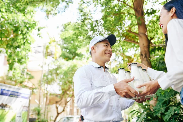 Ευτυχισμένος Χαμογελαστός Βιετναμέζος Ντελιβεράς Που Δίνει Μπουκάλια Γάλακτος Όμορφη Νεαρή — Φωτογραφία Αρχείου