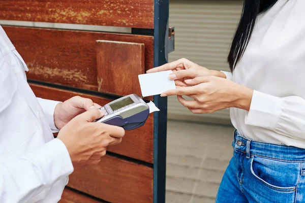 クレジットカードで女性の顧客に支払い端末を与える配達人のクローズアップイメージ — ストック写真