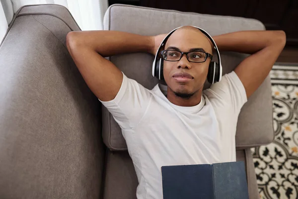 Retrato Joven Negro Sonriente Descansando Sofá Con Auriculares Mirando Hacia —  Fotos de Stock