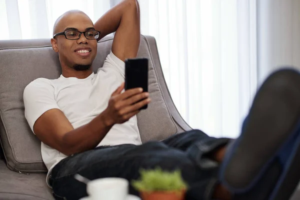 Handsome Young Smiling Black Man Relaxing Comfy Sofa Home Taking — Stock Photo, Image