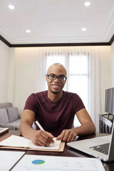 ポジティブなはげ若いですアフリカ系アメリカ人男性座って机に家と充填プランナー — ストック写真