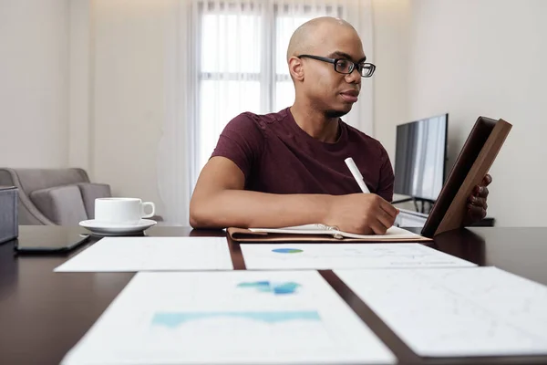 Joven Empresario Afroamericano Serio Analizando Informe Sobre Tableta Tomando Notas —  Fotos de Stock