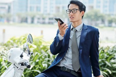 Gözlüklü genç işadamı meslektaşı için sesli mesaj kaydediyor.