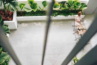 Kafede kahvaltı yapan, tablet bilgisayarda haber okuyan ve sosyal medyayı kontrol eden bir kadın.