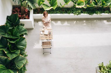 Genç bir kadın kafede tek başına yemek yiyor ve e-kitap okuyor.