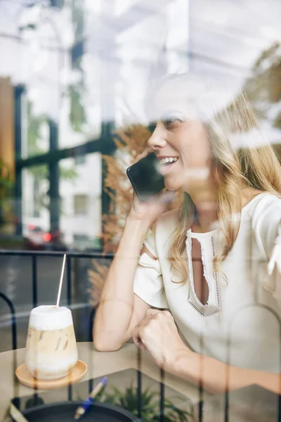 Positive Junge Hübsche Frau Sitzt Cafétisch Und Telefoniert Mit Freundin — Stockfoto