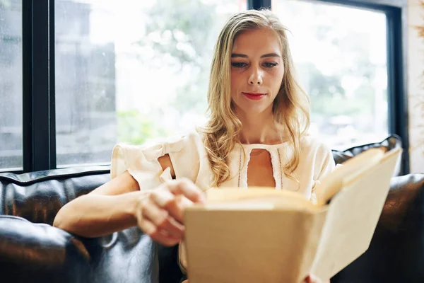 Genç, güzel sarışın kadın ilginç bir roman okuyor.