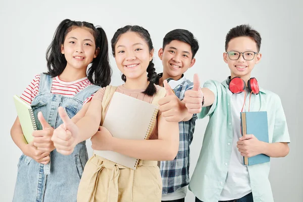 Kitapları ve fotokopi kitaplarıyla mutlu Asyalı okul çocukları.