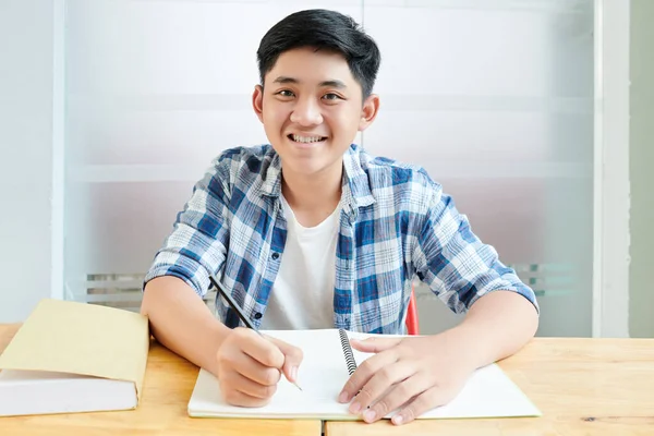 Masada Otururken Yazı Yazan Çizen Gülümseyen Asyalı Öğrencinin Portresi — Stok fotoğraf