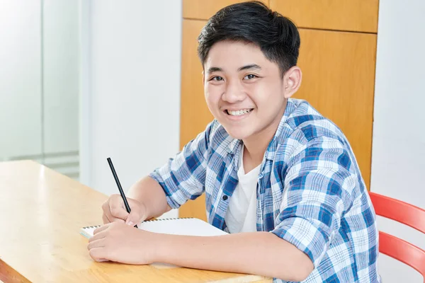 Uśmiechnięty Azjatycki Uczeń Koszuli Kratę Siedzi Przy Biurku Rozwiązuje Równania — Zdjęcie stockowe
