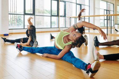 Esnek, genç ve güzel bir kadın yoğun bir antrenmandan önce bacaklarını açıp eğiliyor.