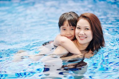 Güzel Vietnamlı kadın ve kızının yüzme havuzunda vakit geçirdiği portre.