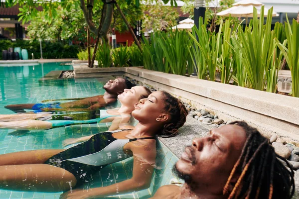 Grupo Multiétnico Jóvenes Tumbados Piscina Con Los Ojos Cerrados Disfrutando — Foto de Stock