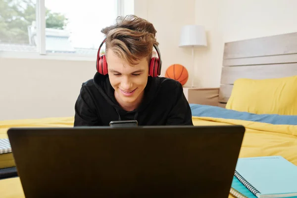 Χαμογελώντας Έφηβος Αγόρι Κάθεται Στο Κρεβάτι Ανοιχτό Φορητό Υπολογιστή Και — Φωτογραφία Αρχείου