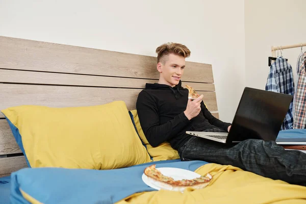 Gülümseyen Genç Çocuk Yatakta Dinleniyor Lezzetli Pizzalar Yiyor Dizüstü Bilgisayarında — Stok fotoğraf