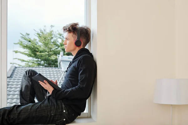 Pensive Tiener Jongen Zit Vensterbank Met Tablet Computer Koptelefoon Weg — Stockfoto