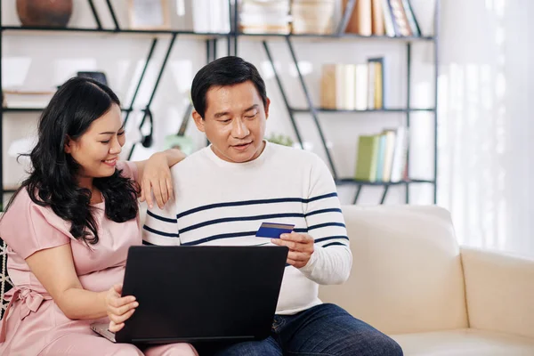 Glückliches Reifes Vietnamesisches Paar Sitzt Auf Sofa Mit Laptop Kauft — Stockfoto