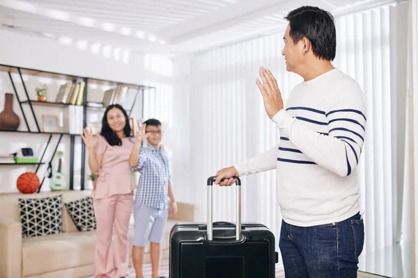 亚洲男子外出出差时 提着手提箱向他的妻子和十多岁的儿子挥手 — 图库照片