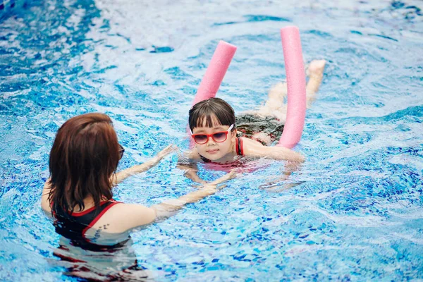 Mujer Joven Controlando Pequeña Hija Nadando Con Fideos Flotantes — Foto de Stock