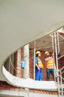 İnşaat halindeki binanın duvarındaki metal gaz borularını kontrol eden çok ırklı ustabaşı.