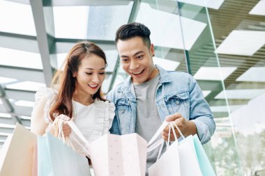Alışveriş merkezinden alışveriş yaptıktan sonra kese kağıdına bakan heyecanlı genç Vietnamlı çift