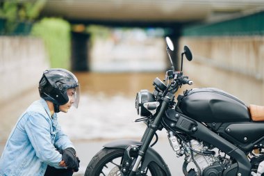 Kasklı ciddi Vietnamlı motorcu motosikletin farına bakıyor.