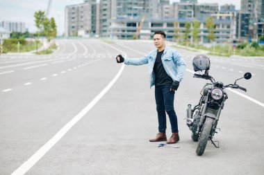 Ciddi bir Asyalı motosikletçi yolda giderken yolda araba yakalıyor.