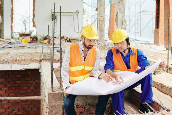 Allvarliga Multietniska Byggare Sitter Rummet För Byggnad Uppbyggnad Och Diskuterar — Stockfoto