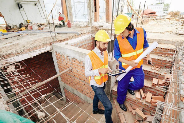 Ciddi inşaatçılar tuğla merdivenlerden çıkıp bugünkü iş planlarını tartışıyorlar.