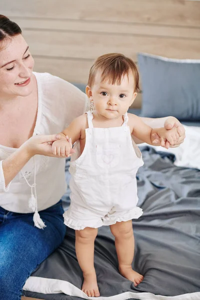 Mujer Sonriente Apoyando Adorable Hijita Aprendiendo Caminar Sobre Cama — Foto de Stock