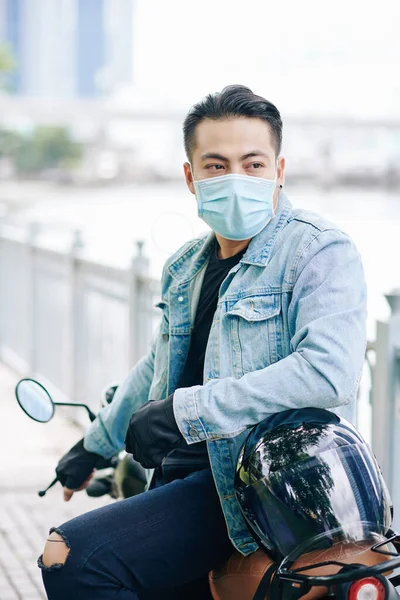 戴医疗面具的英俊摩托车手坐在自行车上远眺的画像 — 图库照片
