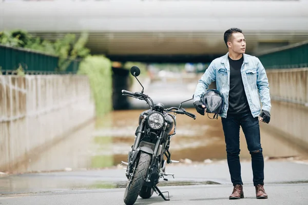 Kot Ceketli Yakışıklı Asyalı Adam Elinde Kaskla Motosikletinin Yanında Duruyor — Stok fotoğraf