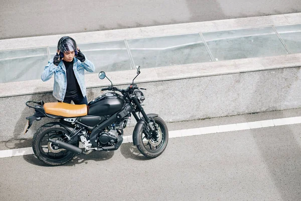 Motorcu otoyolda durdu, motosikletinin yanında durdu ve kaskını çıkardı.