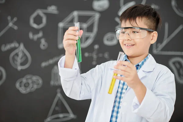 Opgewonden Kleine Wetenschapper Kijkt Naar Reageerbuisjes Met Groene Gele Vloeistoffen — Stockfoto