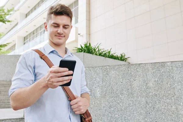 Pozitivní Mladý Podnikatel Chůze Venku Kontrolu Textových Zpráv Smartphonu — Stock fotografie