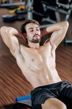 Gömleksiz yakışıklı formalı genç adam spor salonunda mekik çekiyor.