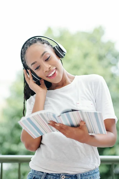 英語の教科書で練習している若い女性は ヘッドフォンでスピーカーを聞いて 彼の後を繰り返しています — ストック写真