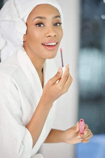 Retrato Bela Jovem Mulher Negra Roupão Aplicando Batom Líquido Rosa — Fotografia de Stock