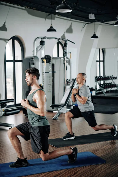 Karışık ırk adamı antrenöründen sonra tekrarlıyor ve spor salonundaki spor paspasına tırmanıyor.