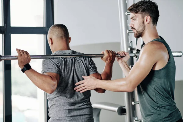 Seriöser Fitnesstrainer Kontrolliert Klient Beim Heben Schwerer Langhantel — Stockfoto