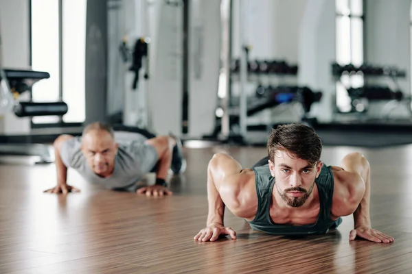 Bonito Jovem Treinador Fitness Mostrando Meia Cobra Push Ups Para — Fotografia de Stock