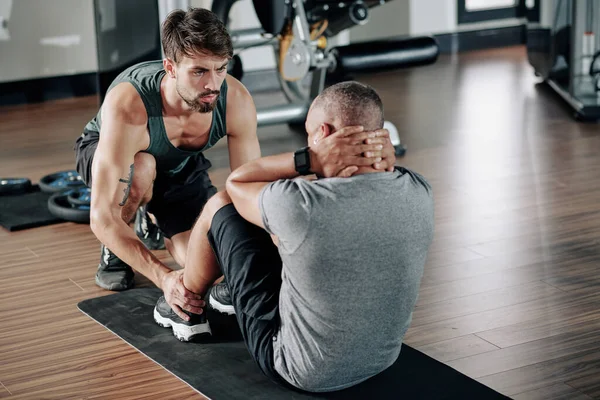 Franzindo Treinador Fitness Sério Ajudando Homem Fazer Abdominais Crunches Tapete — Fotografia de Stock