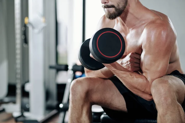근육질 남자가 이두근을 펌프질하기 무거운 덤벨을 가지고 운동을 — 스톡 사진