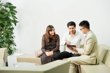 Genç işadamı koltuğunda oturup dijital tablette iş görüşmeleri sırasında internetten sunum yapıyor.